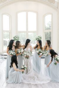 bridesmaids helping bride with dress and veil