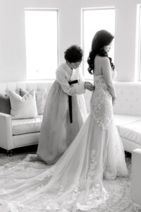 brides mom helps zip up wedding dress