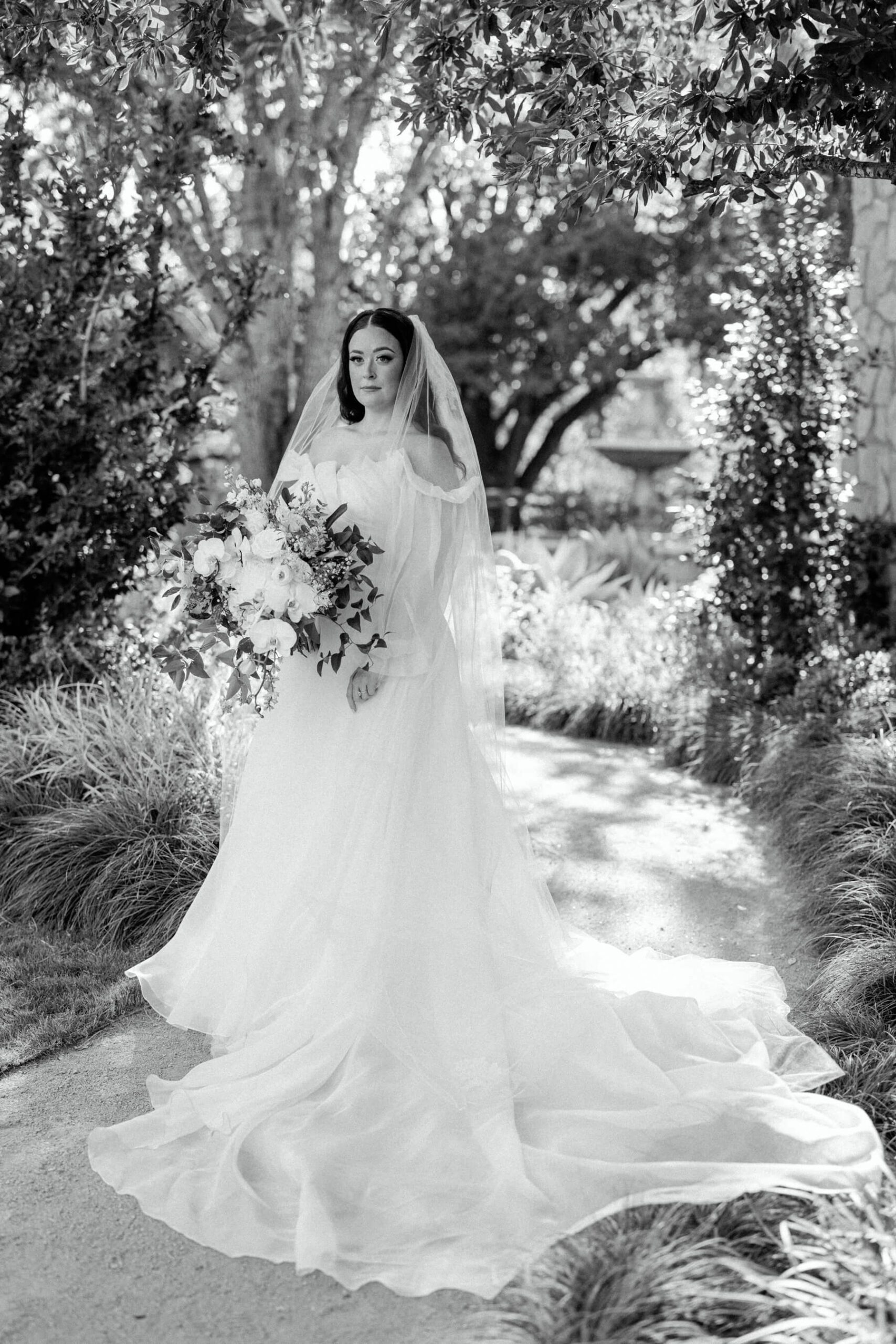 Black and white photo of bride in off the shoulder gown looking off into the distance