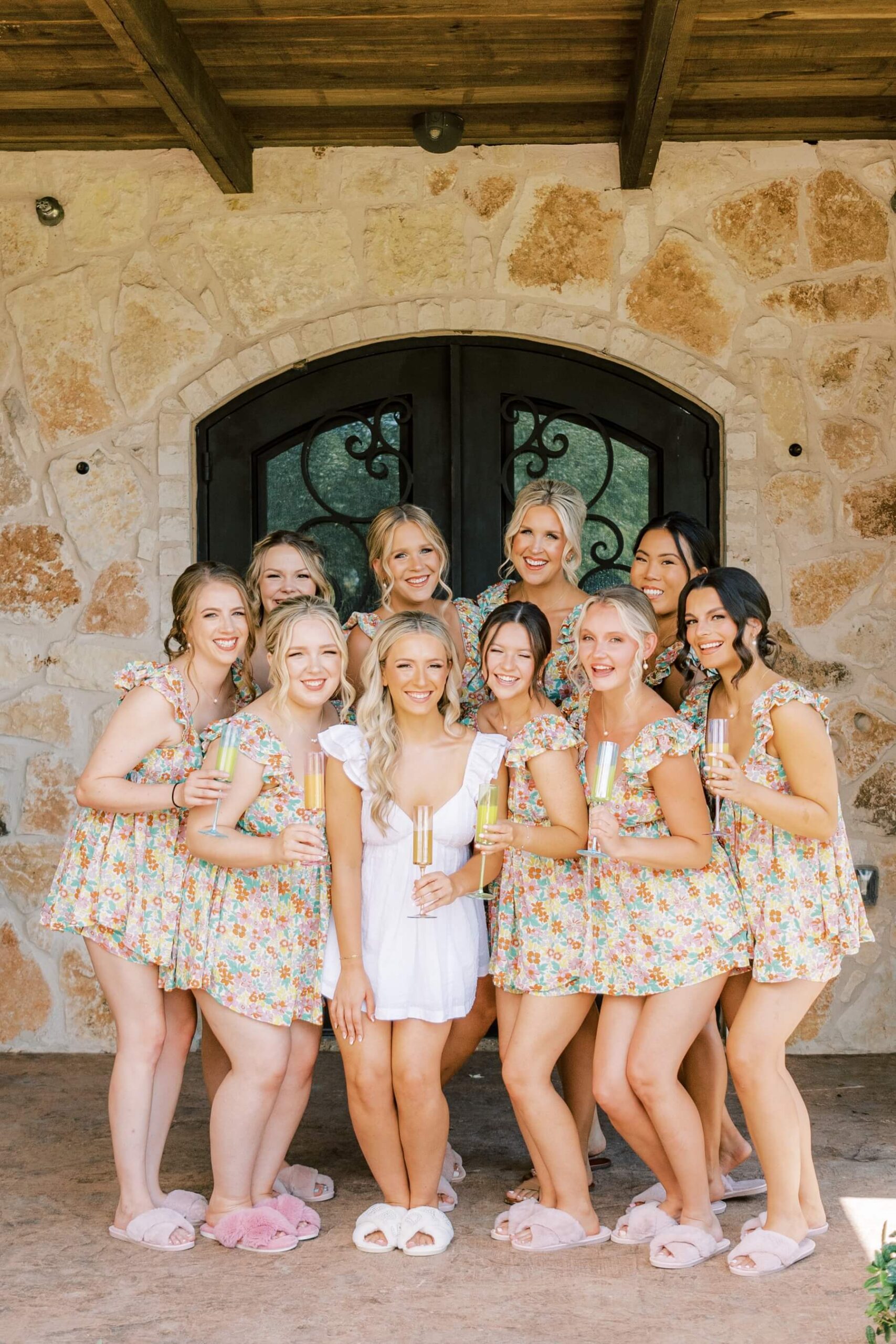 Bride with bridesmaids in floral pajamas holding mimosas 