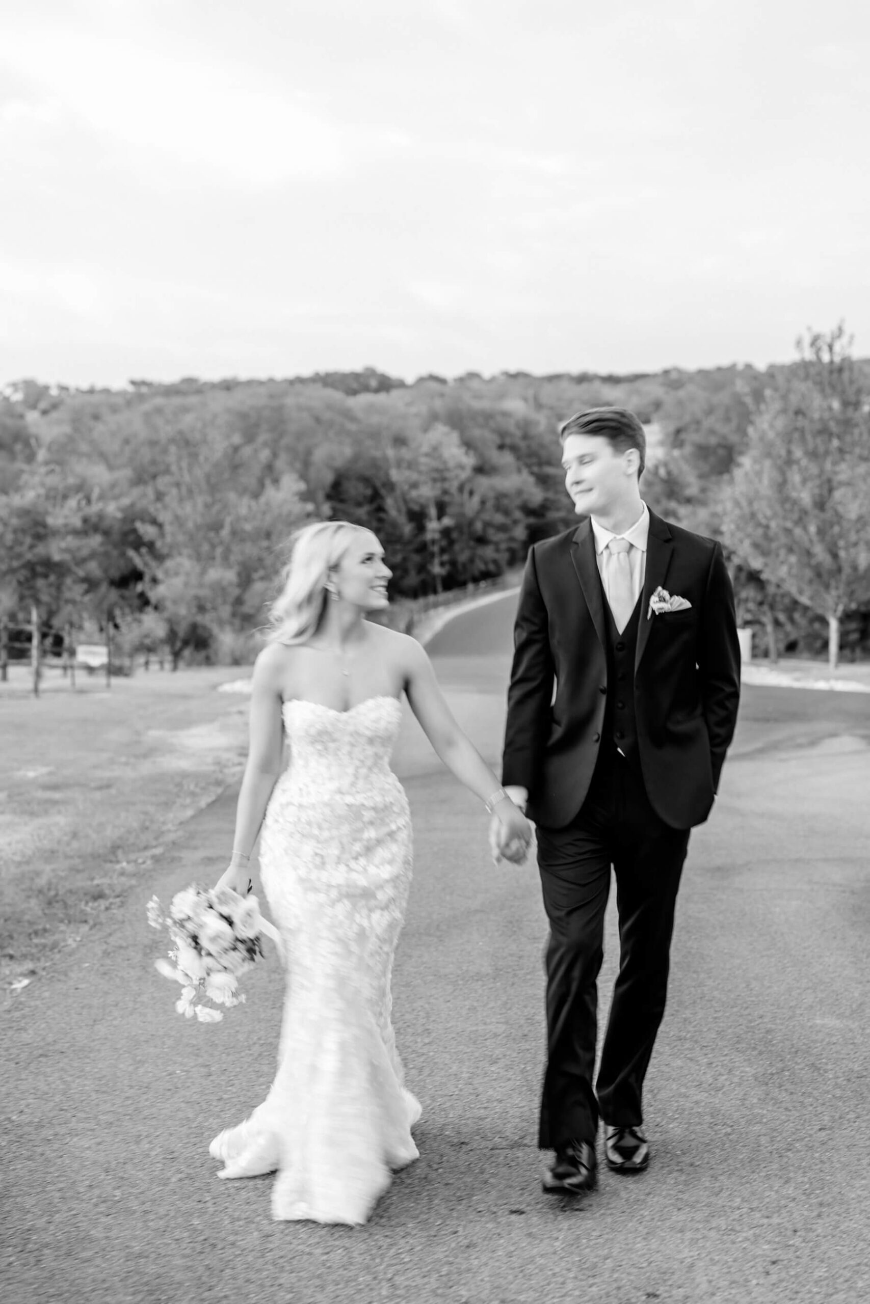 Bride and groom holding hands and walking on road at The Springs in McKinney