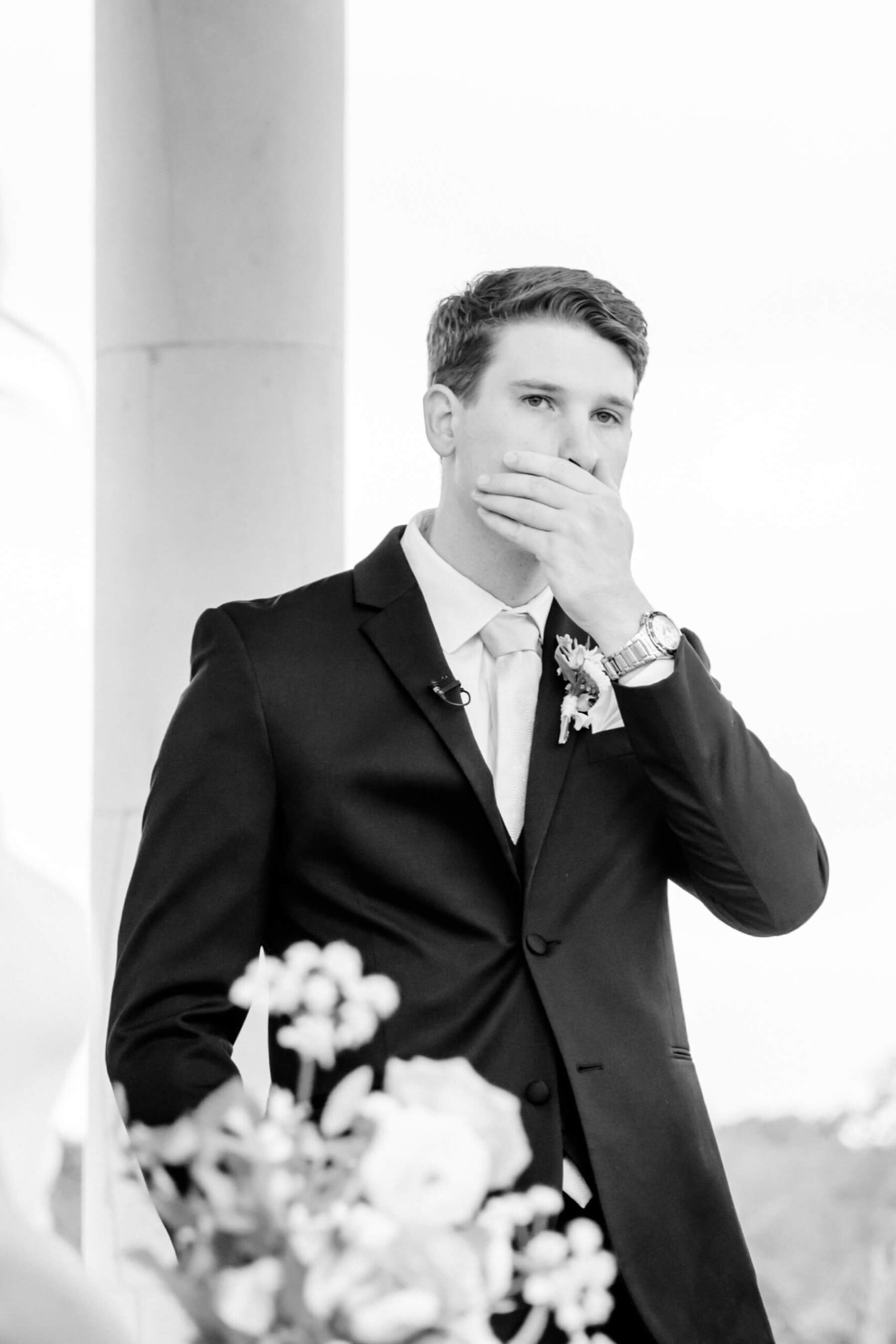 Groom placing his hand over mouth as bride walks down the aisle