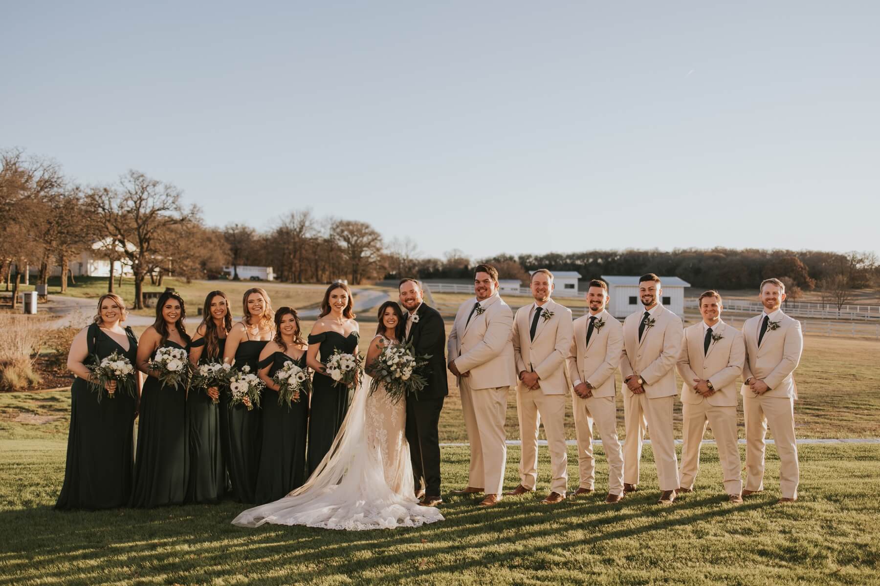 Bride and groom with wedding party in open field with florals designed by Edwards Floral Design in post about wedding florists in Dallas