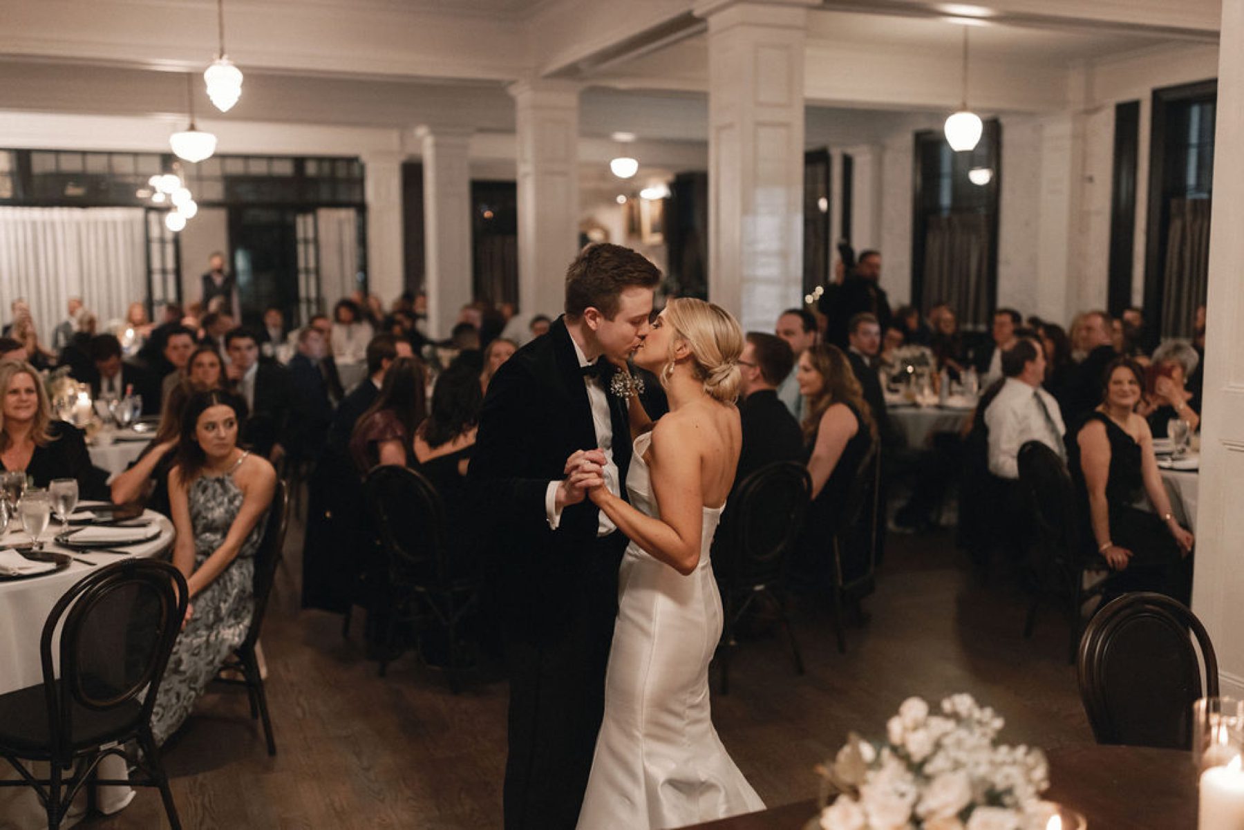 Bride and groom dancing and kissing while guests look on at The Mason Dallas