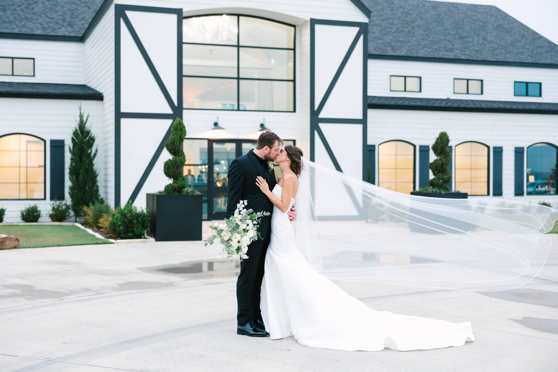 Bride and groom kissing in front of The Gardenia, a wedding venue in North Texas
