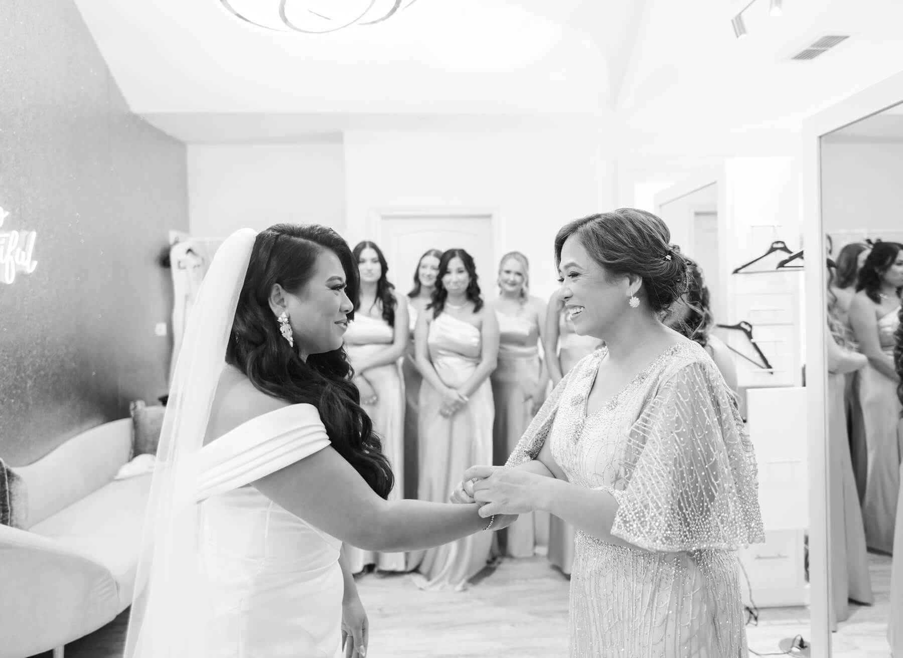 Bride looking at mom as she puts on bracelet while bridesmaids look on