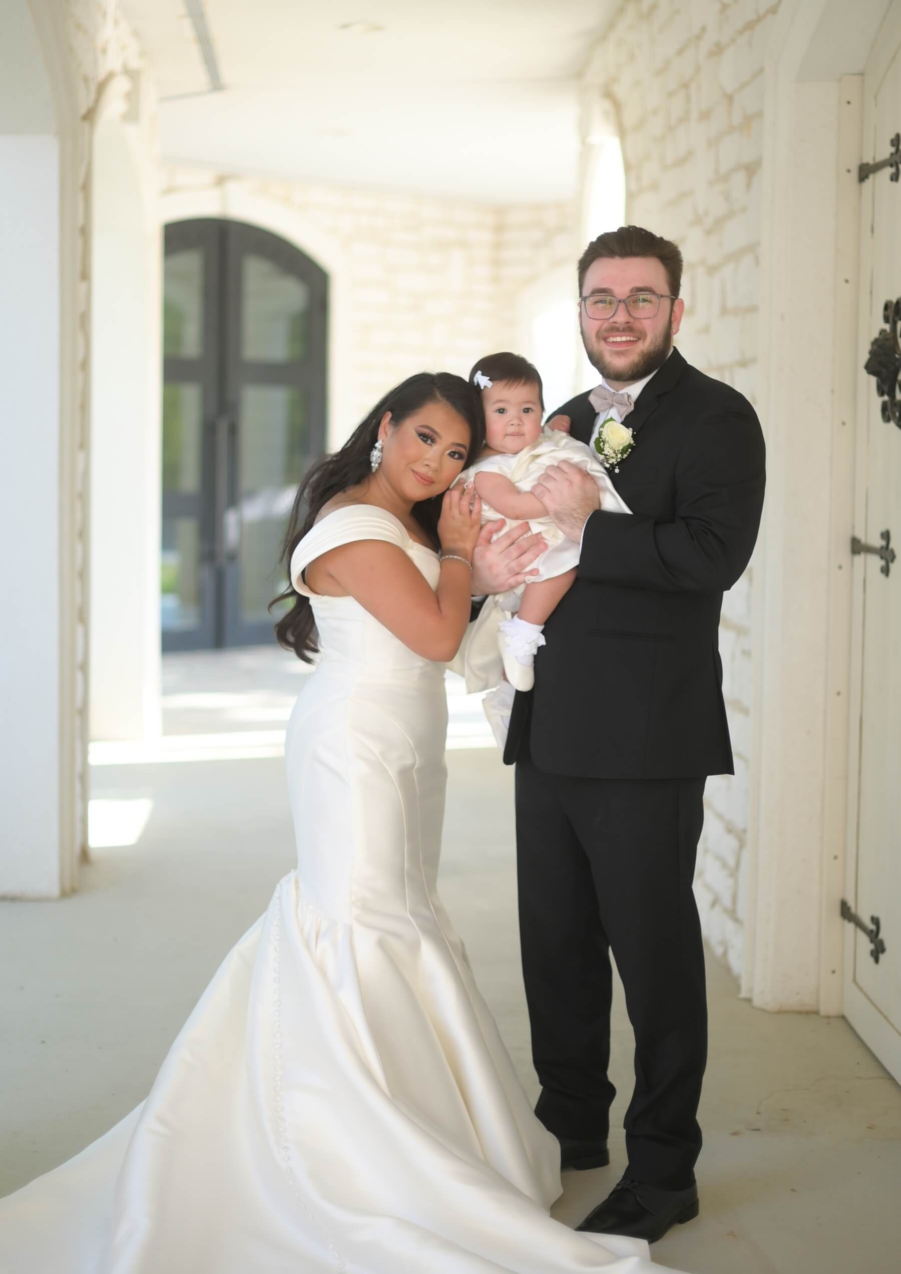 Bride and groom with their baby on their wedding day