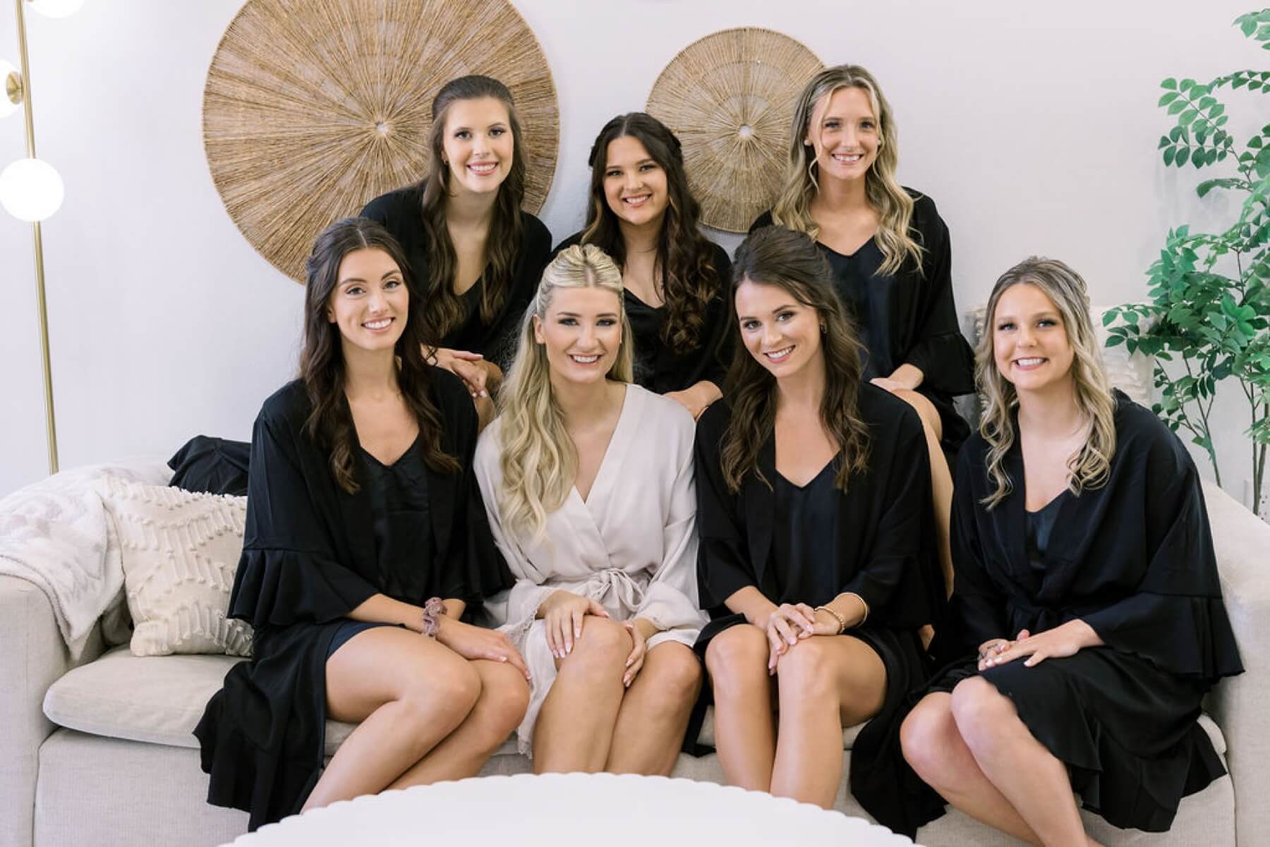 Bride wearing white robe with bridesmaids in black robes