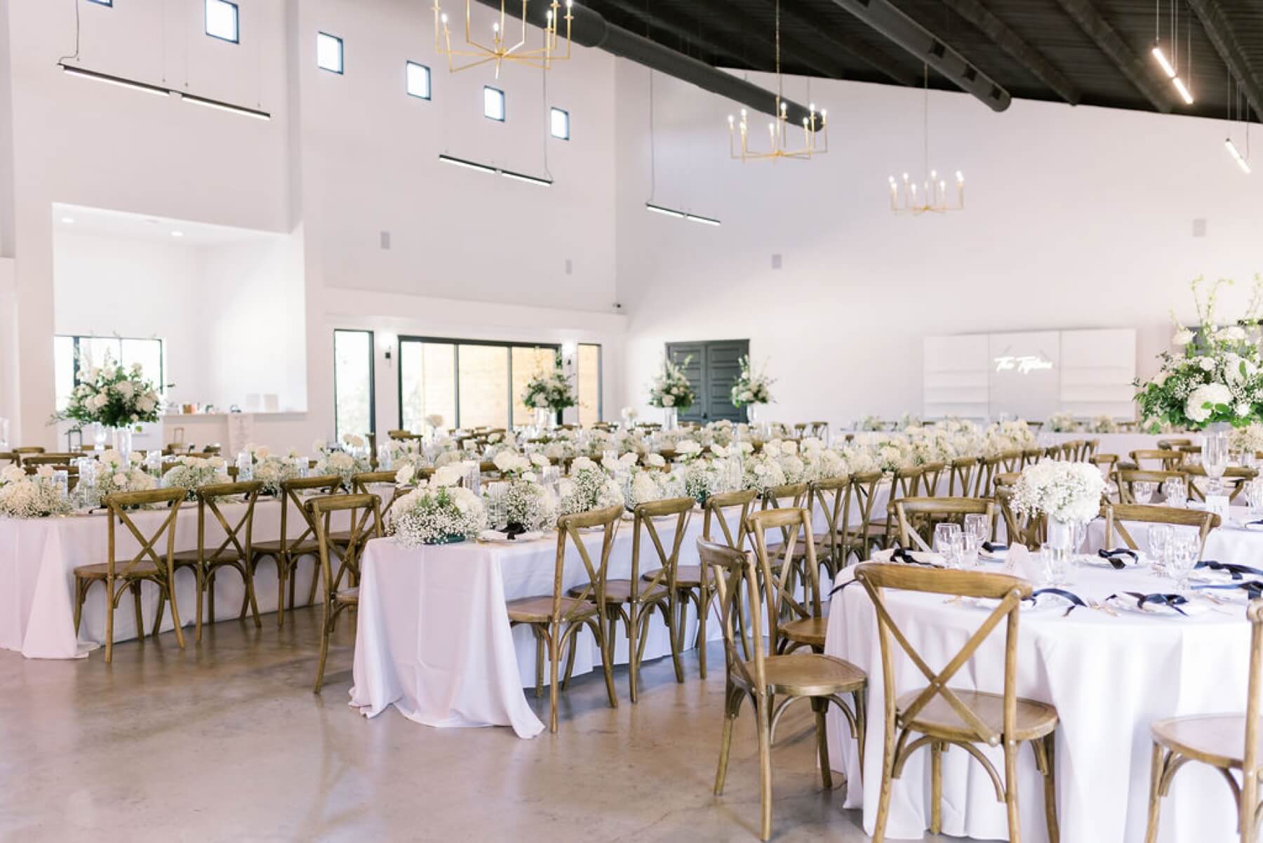 White floral arrangements on tables with brown cross back chairs at Union House TX