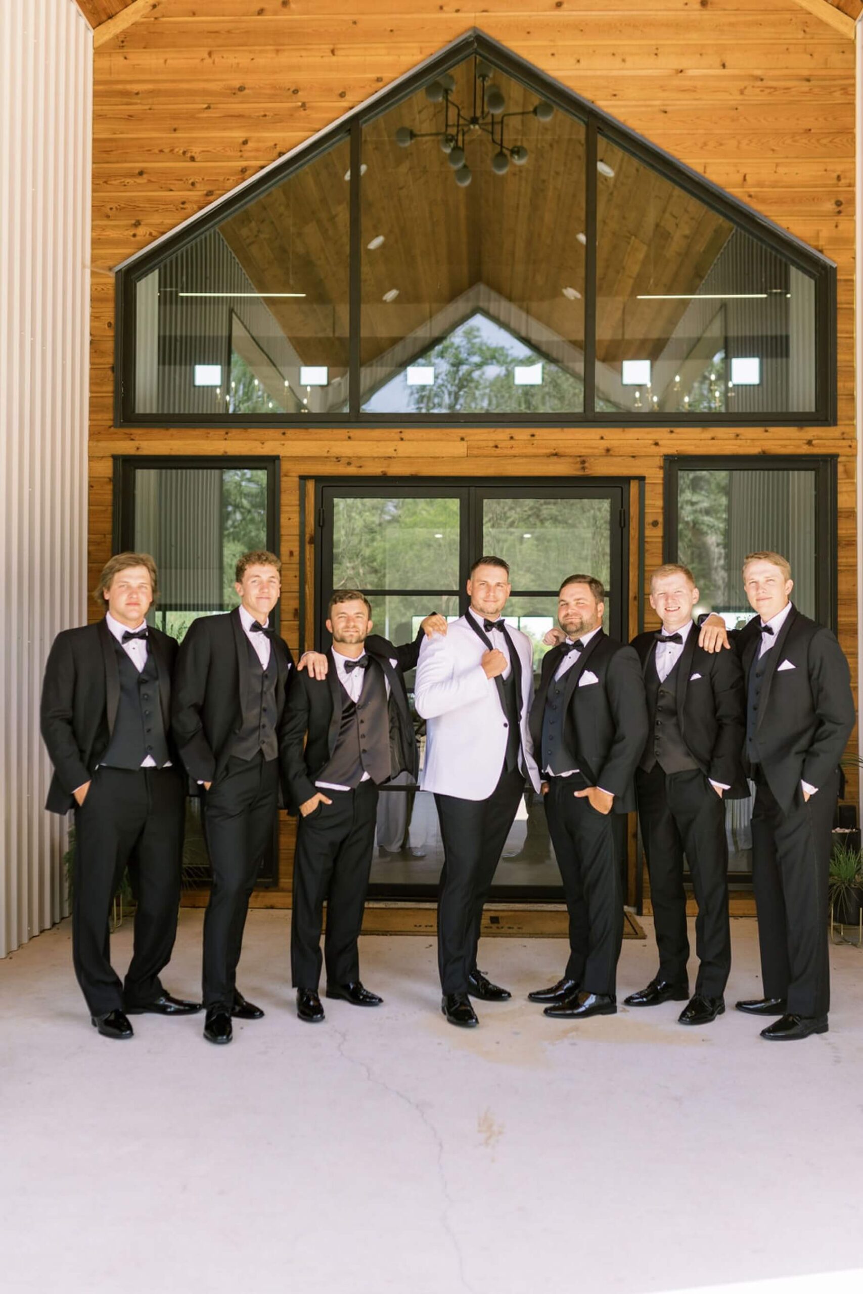 Groom wearing white suit jacket with groomsmen in black suits at Union House TX