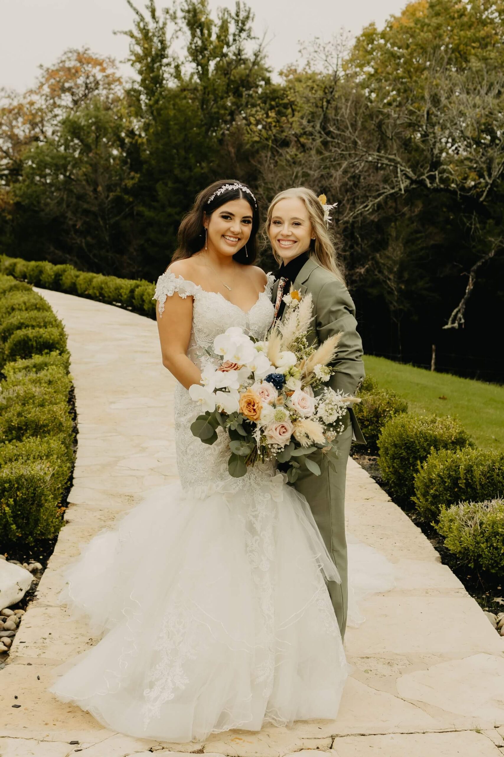 Married couple in wedding dress and green suit with boho bouquet at The Springs McKinney Stone Hall