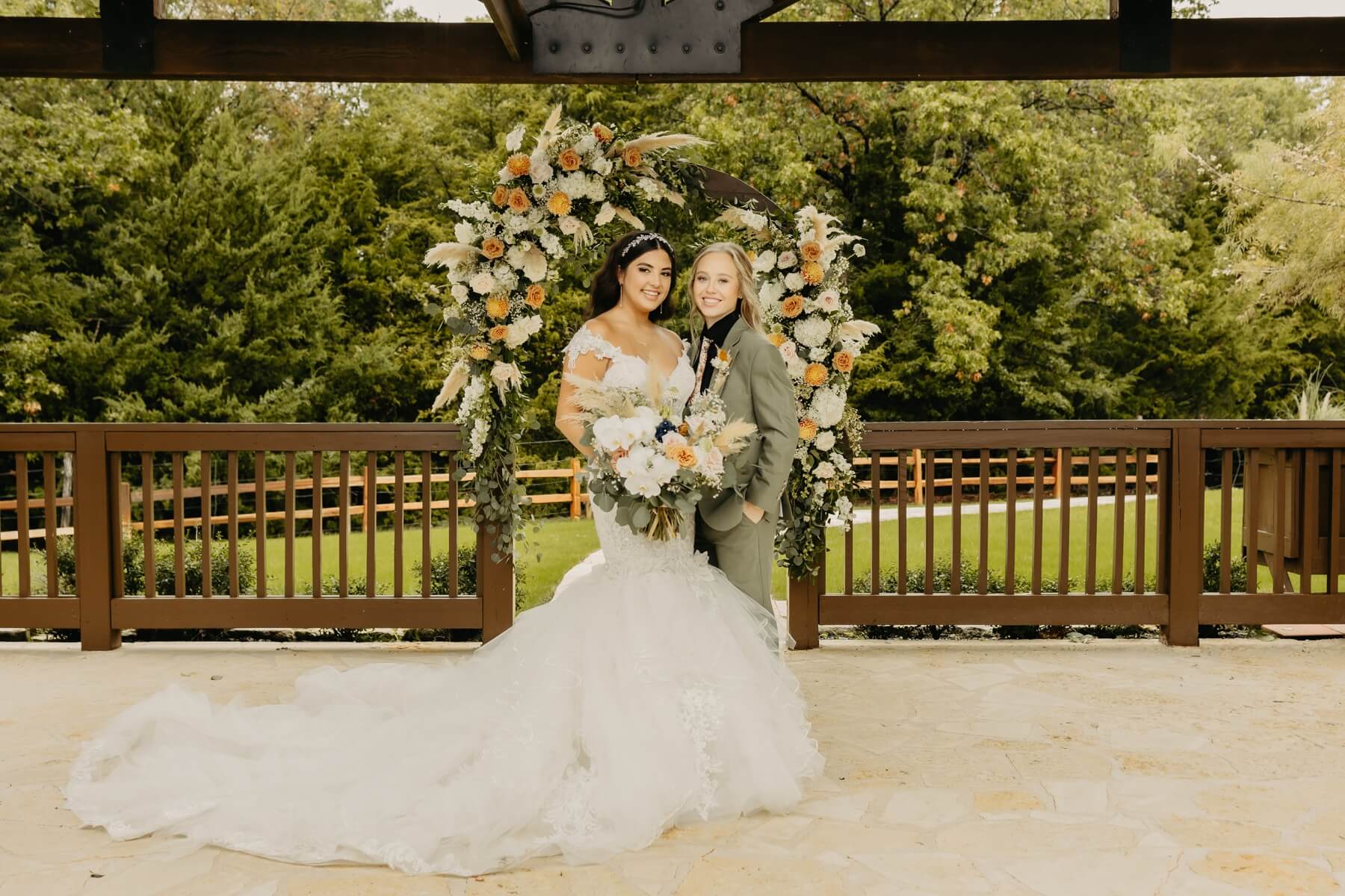 Couple standing in front of boho floral arch at outdoor pavilion at The Springs McKinney Stone Hall