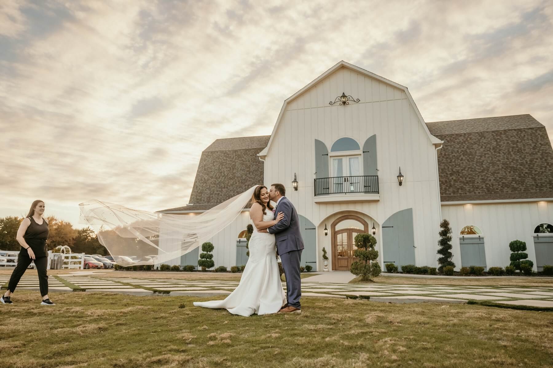 Bride and groom taking golden hour photos in front of The French Farmhouse Venue