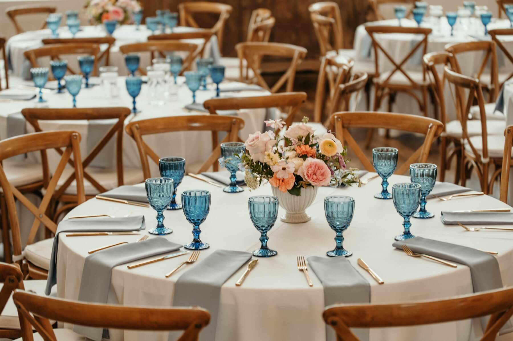 Circle table with blue water glasses, blue napkins, and colorful flowers