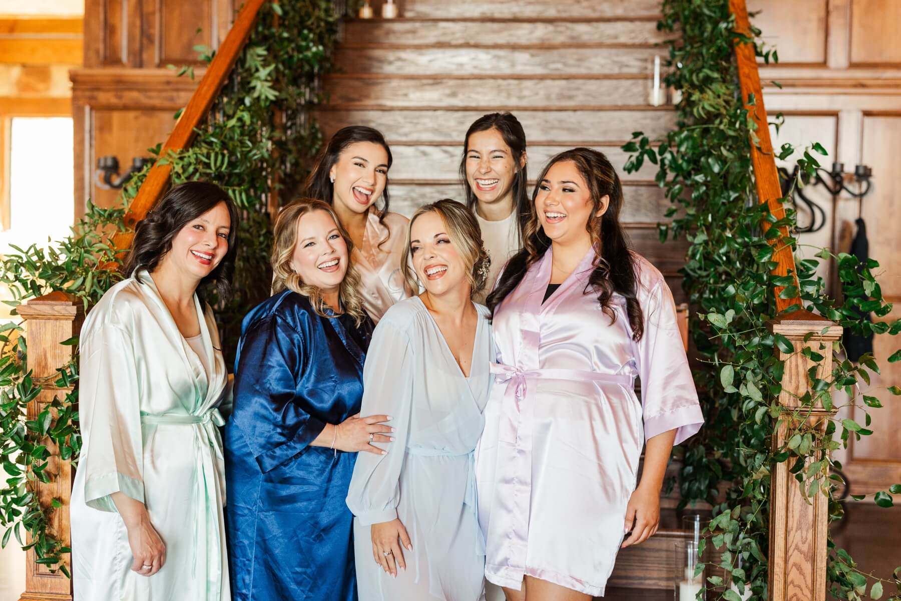 Bride laughing with bridesmaids in robes before getting dressed