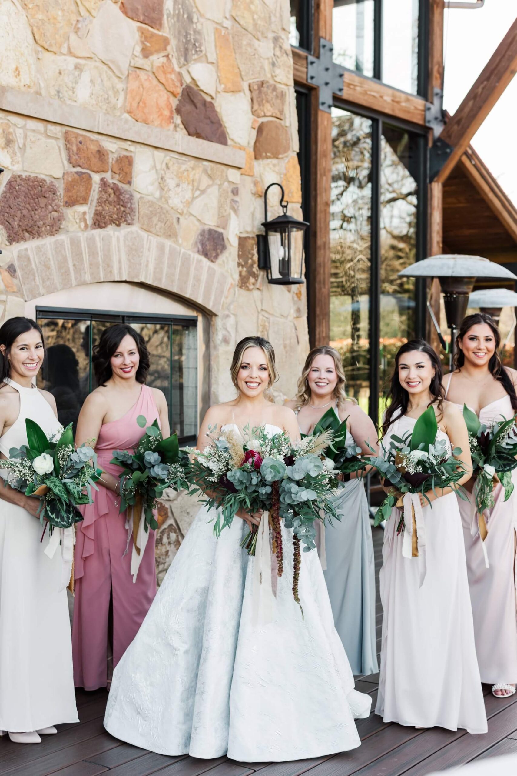 Bride with bridesmaids holding bouquets full of greenery