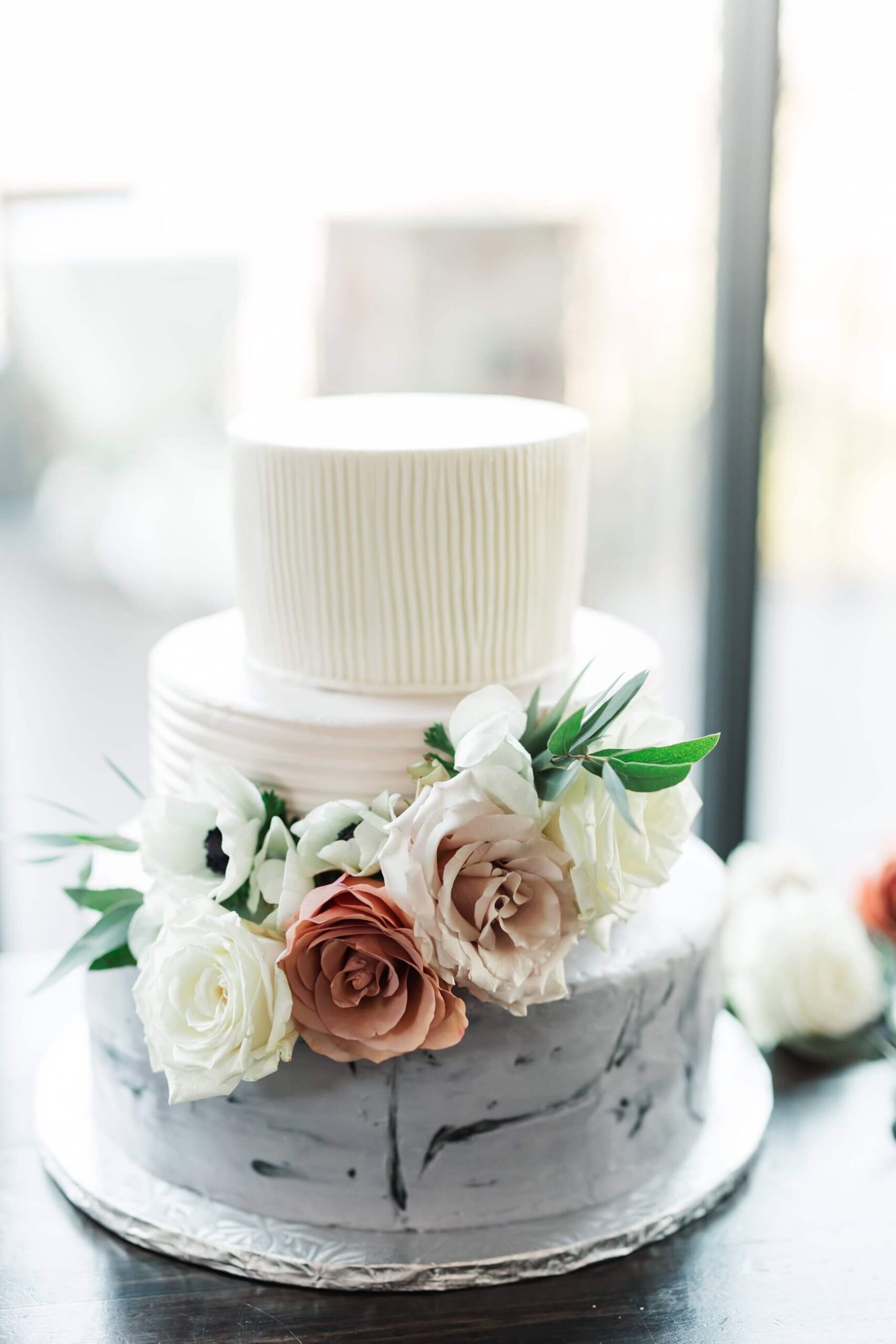 Three tier wedding cake with mismatched icing and floral decorations