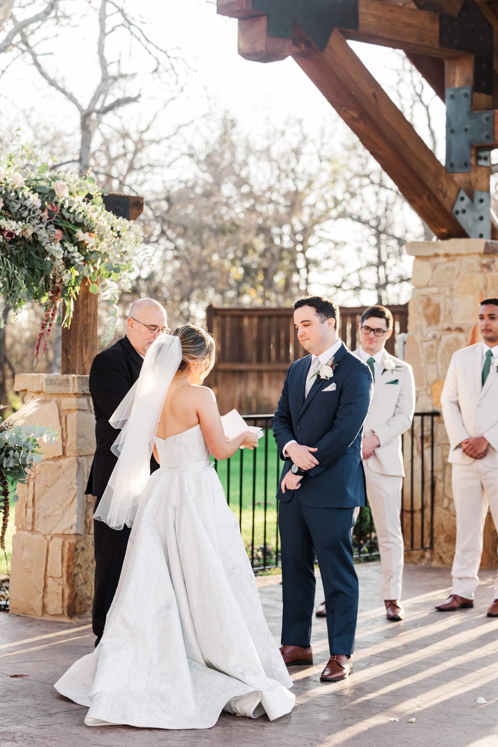 Groom looking at bride as she reads vows