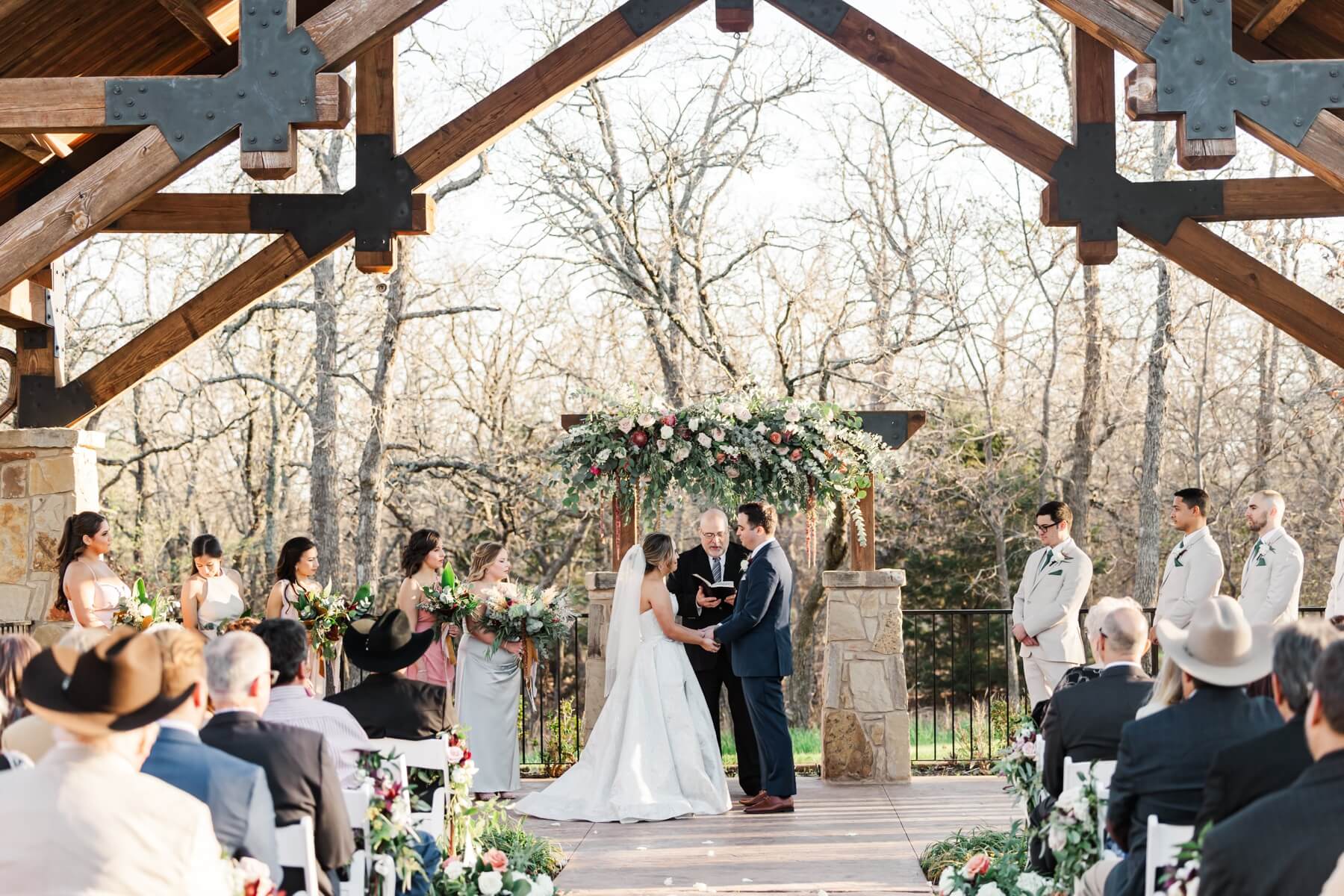 Bride and groom holding hands during outdoor ceremony at The Springs in Denton