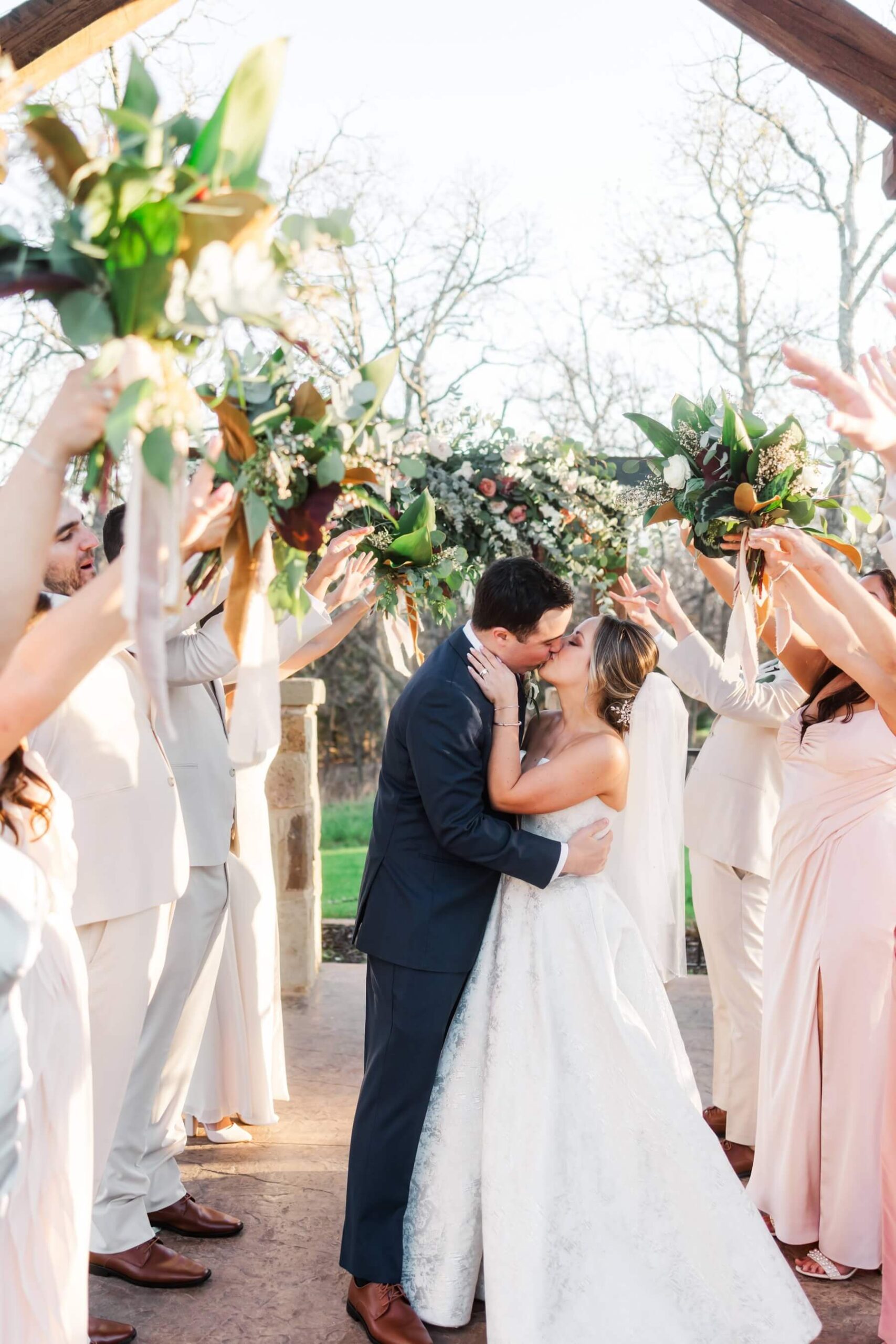 Wedding party making a tunnel while bride and groom kiss underneath them