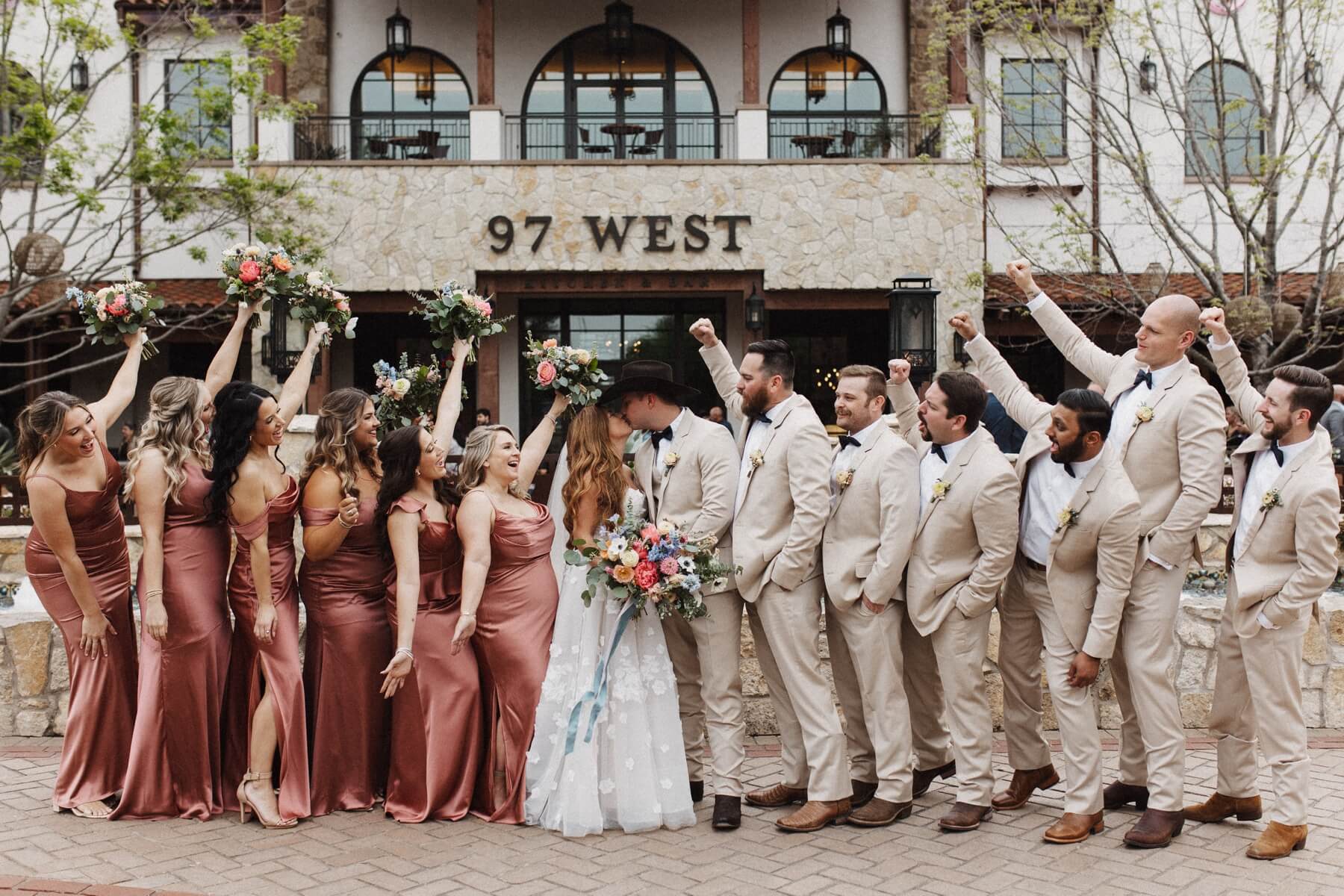 Wedding party cheering as bride and groom kiss